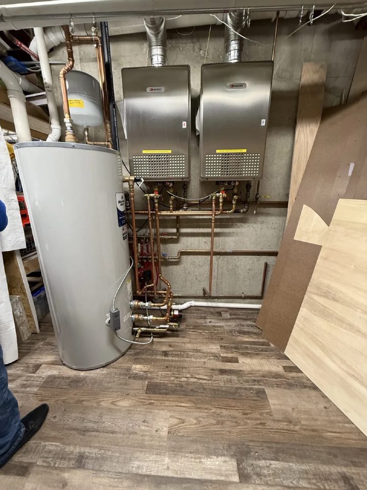 Two wall-mounted tankless water heaters with copper supply lines and an 80-gallon storage tank installed in a Campton Hills basement