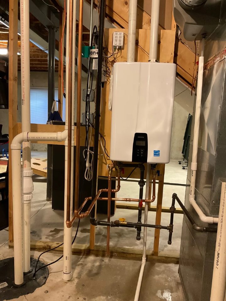 Wall-mounted tankless water heater installed in a Geneva basement with copper supply lines and ENERGY STAR labeling