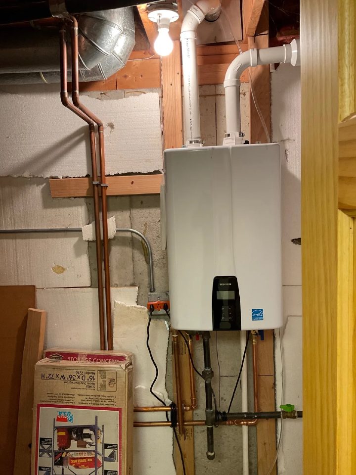 Wall-mounted Navien tankless water heater installed in a Sycamore basement with copper supply lines and concentric venting